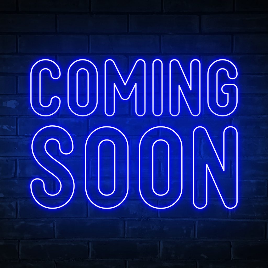 Coming soon - blue neon light word on brick wall background